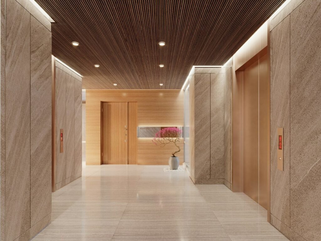 Modern shared building lobby with lift doors, marble walls, timber accents and soft lighting.